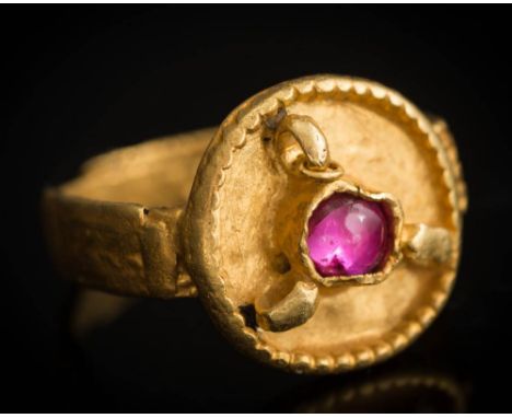 A Saxon migration period gold ring: inset with a later single cabochon ruby, the round bezel with beaded edge and three plain