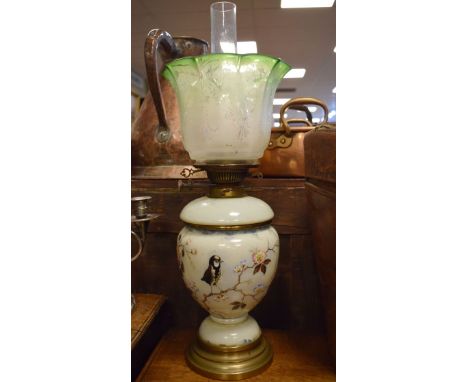 Victorian glass oil lamp having enamelled decoration depicting birds amongst foliage and standing on a brass foot, green etch