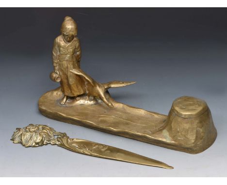 AN ART NOUVEAU GILT BRONZE DESK STAND with ink well in the form of a young girl with a goose, 56cm long and a brass page turn