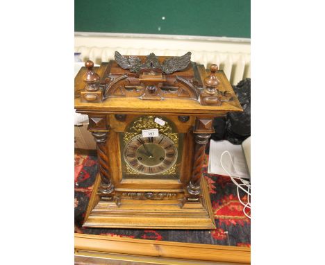 A WOODEN MANTLE CLOCK WITH PART BRASS BASE WITH BARLEY TWIST SIDE SUPPORTS WITH PENDELOM NO KEY , BIRD DECORATION NEED TO BE 