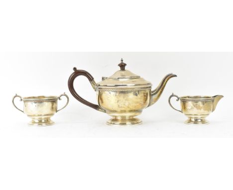 A George V silver three piece tea service, hallmarked Birmingham 1932, consisting of a teapot, milk jug and sugar bowl, the t