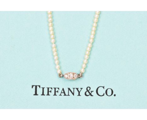 A Tiffany &amp; Co single strand diamond and cultured pearl necklace, the white metal clasp inset with three brilliant cut di
