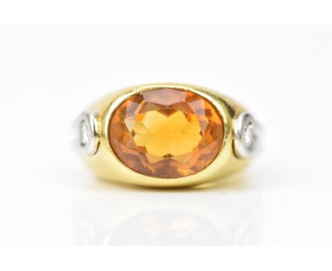 An 18ct bi-coloured gold citrine and diamond ring, having a large faceted oval cut citrine 11.8mm x 9.2mm, flanked by two dia