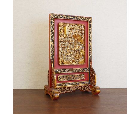 A Chinese gilt lacquered wood table screen,19th century, pierced and carved with figures amongst rocks and pine trees, the bo