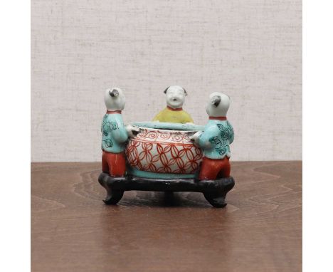 A Chinese wucai brush washer,late Qing dynasty, moulded with three boys carrying a water pot, 9cm long, wood stand (2)清晚期 五彩童