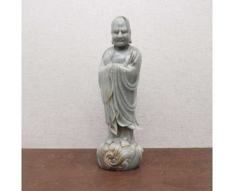 A Chinese jade figure, 20th century, of a luohan wearing a long floating robe, standing on spuming waves, 40.5cm high   Condi