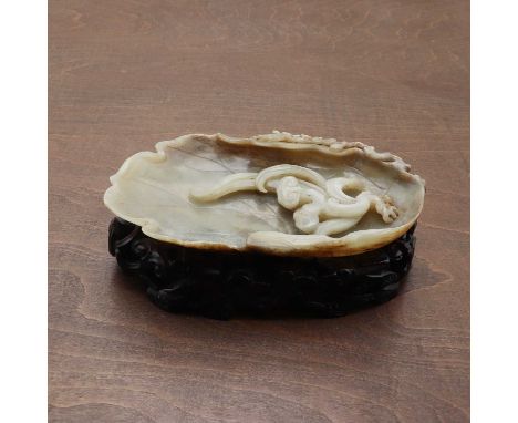 A Chinese jade brush lick,20th century, in the form of a leaf, the centre carved with lingzhi, 17.5cm long, wood stand pierce