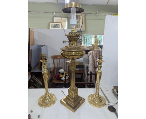 A late 19th/early 20th Corinthian column oil lamp converted to an electrical lamp together with a pair of brass candlesticks 