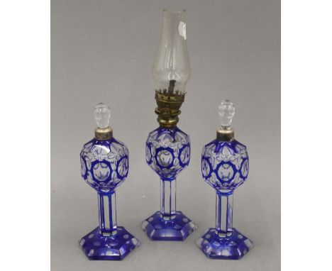 A small blue flashed glass oil lamp and a pair of scent bottles en-suite. The former 27 cm high.