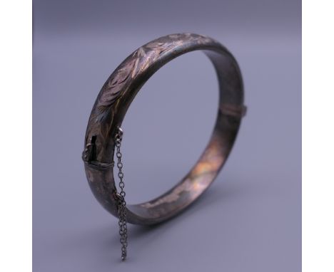 An embossed silver bangle form bracelet. 6.5 cm wide. 15.8 grammes.