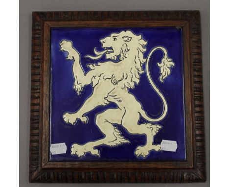 A porcelain tile depicting a rampant lion, set in an oak frame. 28 cm wide.