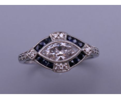 An Art Deco style platinum marquise cut diamond and sapphire ring. Ring size M. 4.2 grammes total weight.