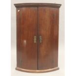 A Georgian mahogany bow front hanging corner cupboard. 87.5 cm high.