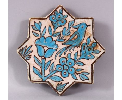 AN IRANIAN TURQUOISE GLAZE STAR FORMED POTTERY TILE, decorated with bird upon branches, 17cm