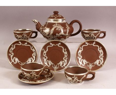 A CHINESE YIXING POTTERY WHITE METAL OVERLAID TEAPOT with four matching cups and saucers, teapot: 19cm wide.