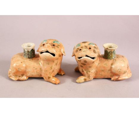 A PAIR OF 19TH / 20TH CENTURY CHINESE FAMILLE ROSE DOG CANDLESTICKS, each dog recumbent with the stick opening to the back, 1