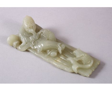 A CHINESE CARVED CELADON JADE FIGURE OF A RECLINED IMMORTAL &amp; FISH, the immortal figure reclined upon a bamboo raft with 