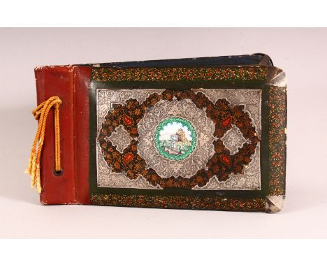 A PERSIAN LACQUER, WHITE METAL &amp; ENAMEL ARTIST BOOK - the cover with in inset enamel plaque of a landscape, held by white