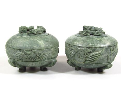 Two polished jade coloured pots, of compressed circular form, with flush lids, each with dragon and orb knops and a bellied c