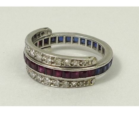 An alternating sapphire and ruby set white metal eternity ring, flanked by two half bands of diamonds, size M, 6.0g.