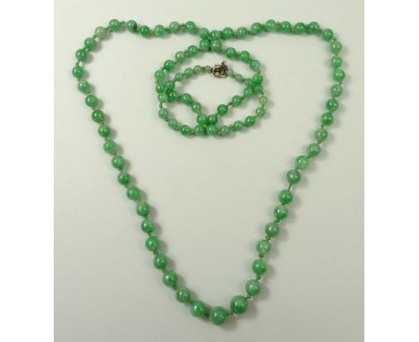 A Chinese apple green jade necklace, of ninety two spherical graduated beads, 65cm long.