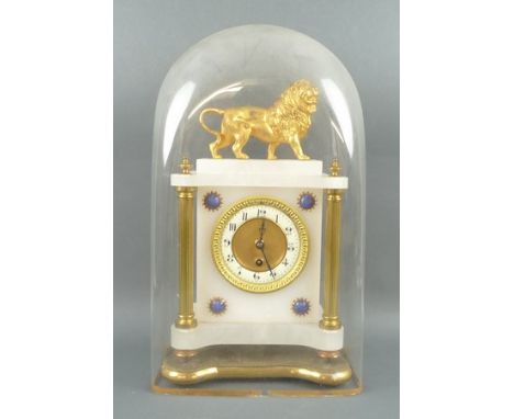 A 1920s alabaster mantel clock, surmounted by a gilded lion, the ceramic dial bearing Arabic numerals, the front with blue ca