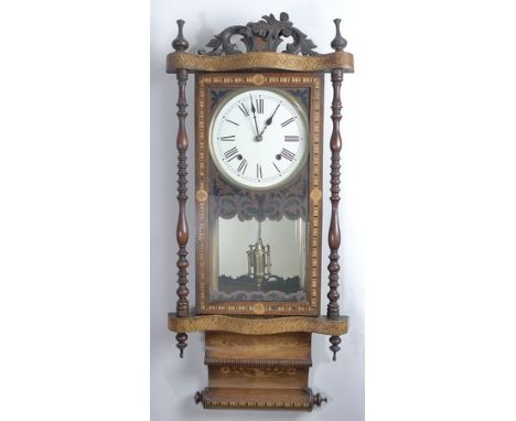 A Victorian walnut and parquetry inlaid wall clock, with spindled uprights and finials, the glazed door housing a white ename
