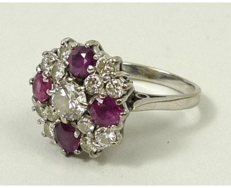 An 18ct white gold, diamond and ruby cluster dress ring, the central diamond, 0.5ct, surrounded by four rubies and four tripl