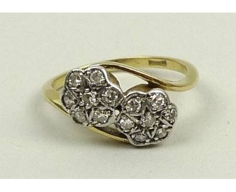 An 18ct gold and diamond double flower head ring in a cross over setting, approximately 1ct total, size K/L, 3.2g.