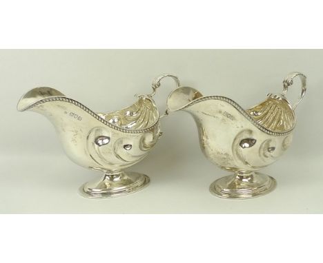 A pair of Edwardian silver sauce boats, manner of Paul Storr, with scrolling shell decoration on a pedestal foot, Josiah Will