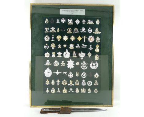 A WWI bayonet and scabbard, and a complete set of cap badges for the regiments and corps of the British army 1980, framed and