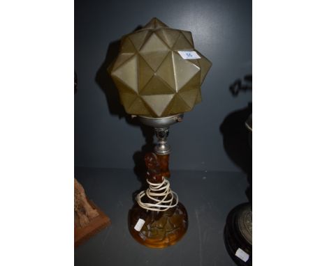 An art deco amber glass desk lamp having figure of naked maiden to base holding star like shade.
