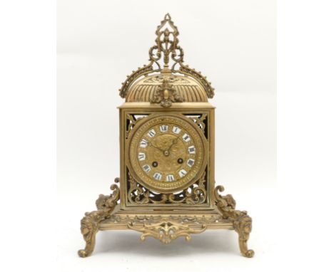 A late nineteenth to early twentieth century ornate brass mantel clock, with a chased dial and porcelain tiles with enamelled