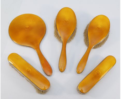 A silver and orange guilloche enamel five piece dressing table set, Birmingham 1929, comprising hand mirror, two hair brushes