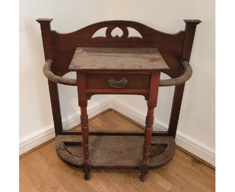 An Edwardian mahogany umbrella hall stand, having central drawer flanked by twin bowed umbrella/stick stands with drip trays 