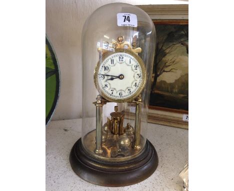 A brass Anniversary clock with enamel dial under glass dome on brass base.