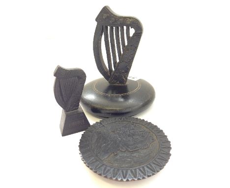 An Irish bog oak harp paperweight together with another smaller and a carved bog oak disk.
(R29)