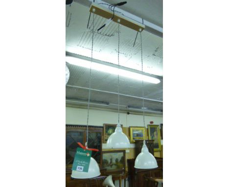 An Industrial-type three lamp hanging ceiling fitting with cream metal shades