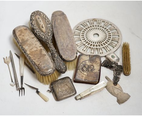 A collection of mostly silver items to include a rattle in the form of a cat, a vesta case, silver backed brushes and a bookm