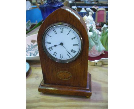 An Edwardian inlaid oak cased mantel clock with an arched case and white enamel dial.