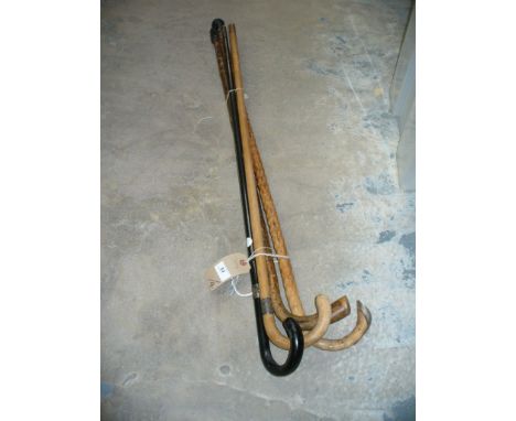 A Silver collared ebonised walking cane, a rustic wooden walking stick with a silver cap, a third walking stick with a silver