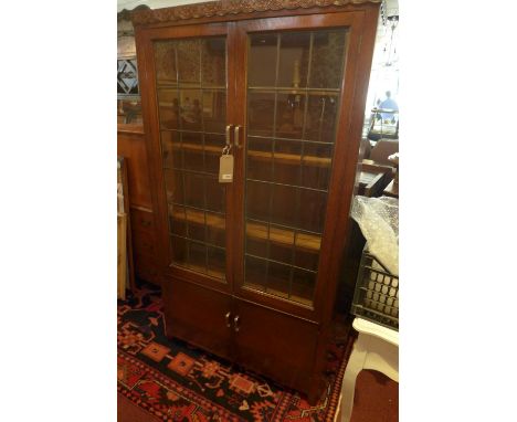 An Art Deco oak bookcase, with two leaded glass panel doors, enclosing adjustable shelves, above two cupboard doors, H.183 W.