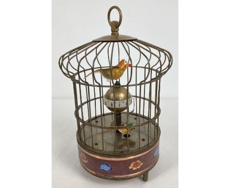 A brass ornamental wind up birdcage clock with winding mechanism to underside and red cloisonne panelled detail. Both birds m