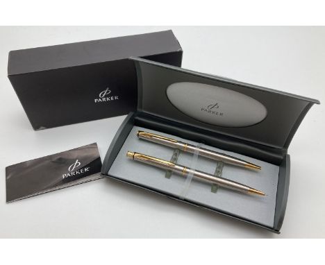 A Parker Insignia propelling pencil and ball point pen set. In brushed silver tone with gold tone features. With original cas