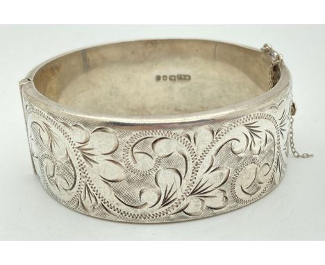 A vintage silver wide, half engraved, hinged bangle with push fastening &amp; safety chain (broken). Engraved with floral and