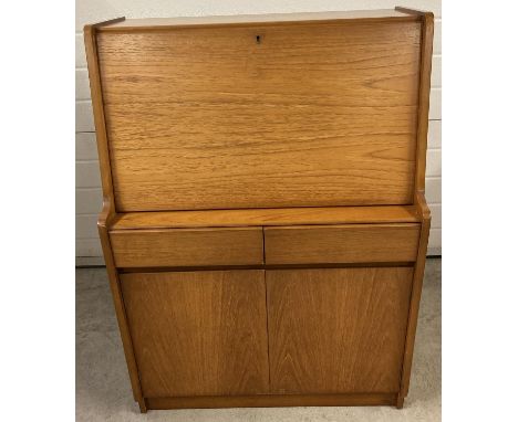 A vintage teak 2 drawer bureau by Remploy complete with key. 2 door cupboard base with interior shelf, pull down top section 