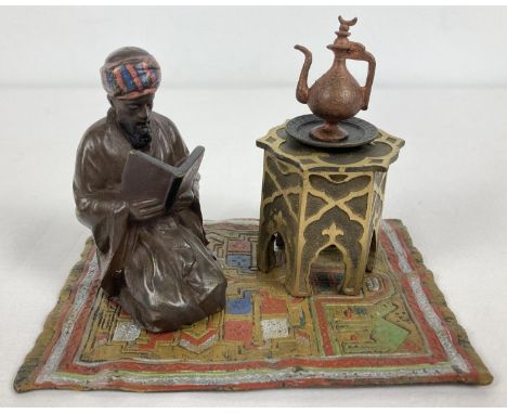 After Bergman - a cold painted Arabian style inkwell.  An Arabian gentleman knelt reading on a colourful carpet beside an ink