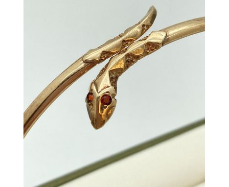 A 9ct gold thin bangle with snakes head &amp; tail detail set with small garnet stones. Approx. 6.5cm diameter. Fully hallmar