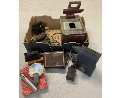 A box of early camera and film equipment. To include an early magic lantern/projector, red developing light, Kobald flash gun