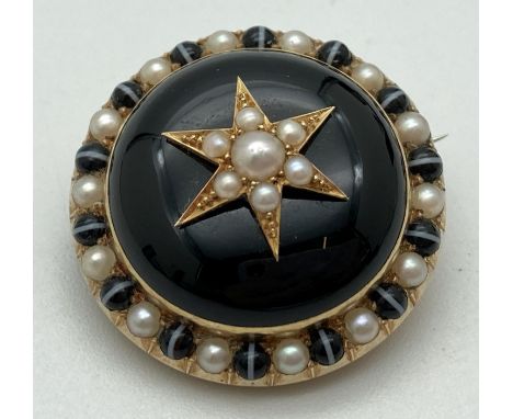 A Victorian gold mourning brooch with black enamelled central panel and set with seed pearls. Reverse has a glass panel to st